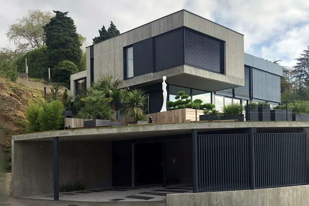 Construction d'une maison d'architecte en béton brut dans la pente